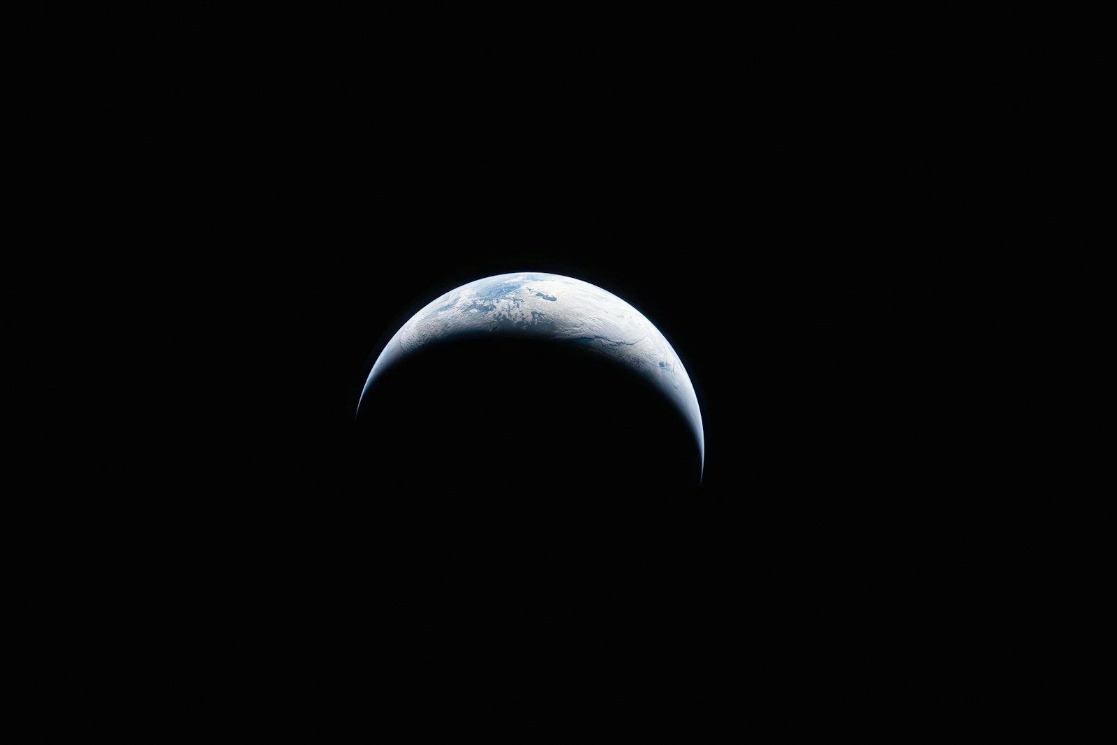 Crescent earth visible in the dark expanse of space